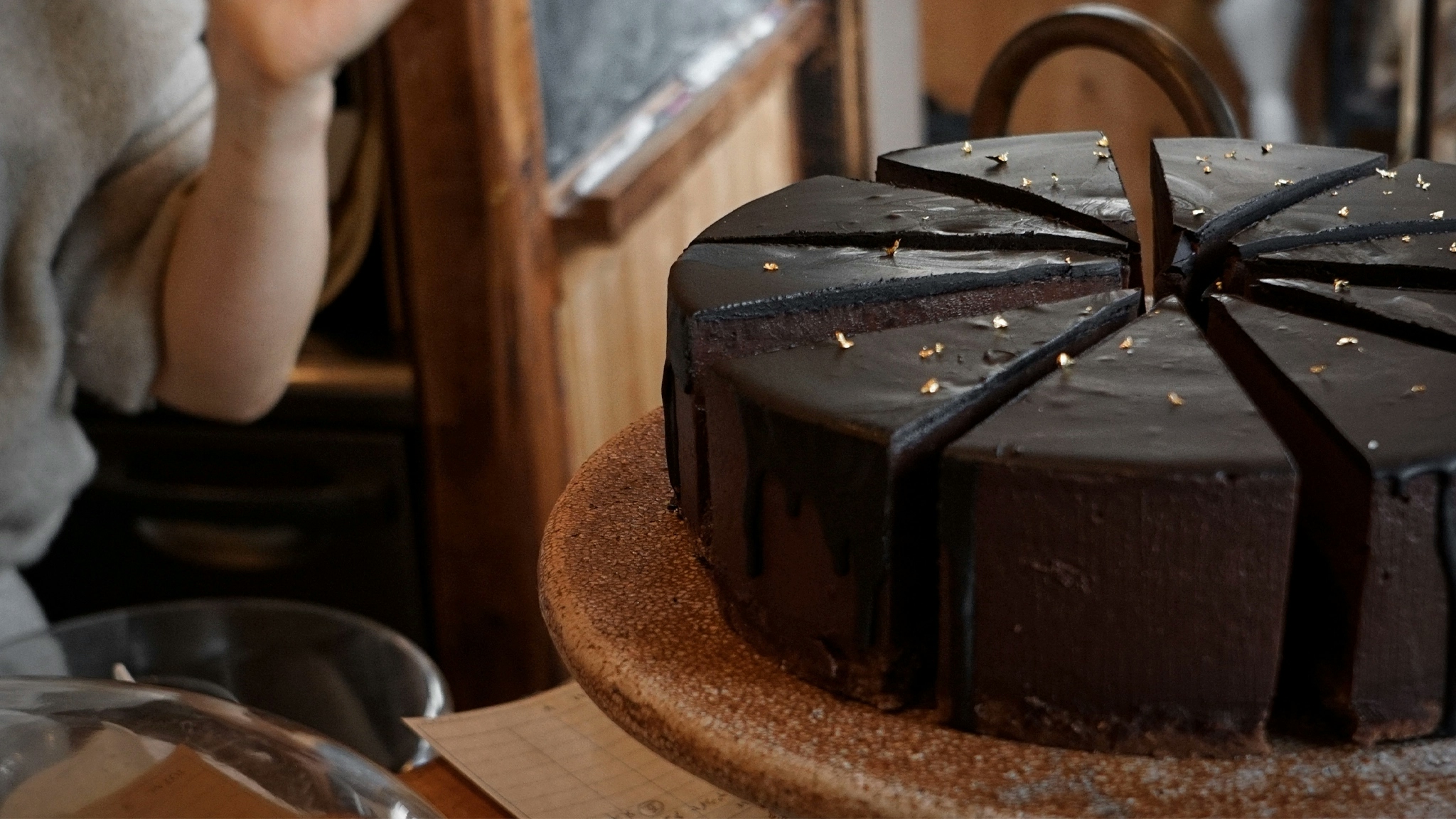A decadent chococlate cakes sits on a counter, uncovered and ready for a slice to be plated