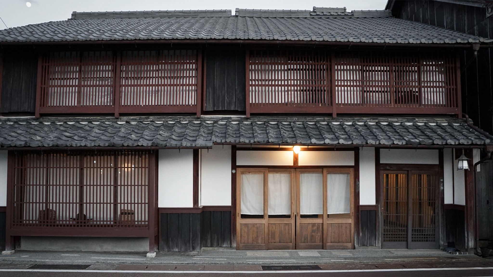The traditional latticed wooden exterior of Fukudaya, painted in carmine red against black and white