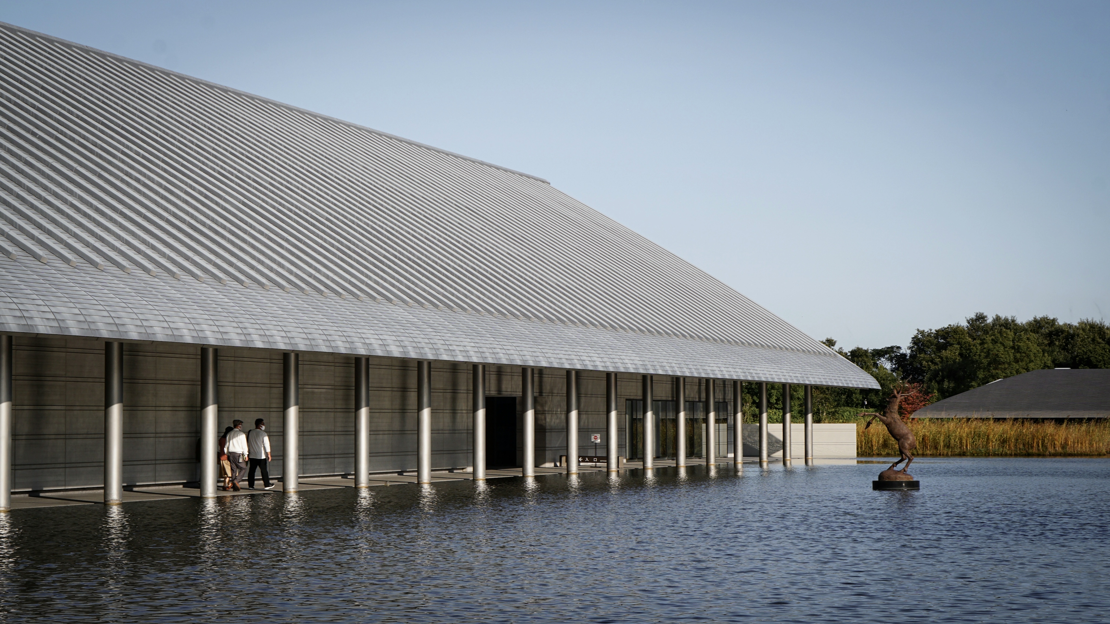 The concrete and steel exterior of Sagawa Art Museum glistens against the sunlight hitting the surrounding pool